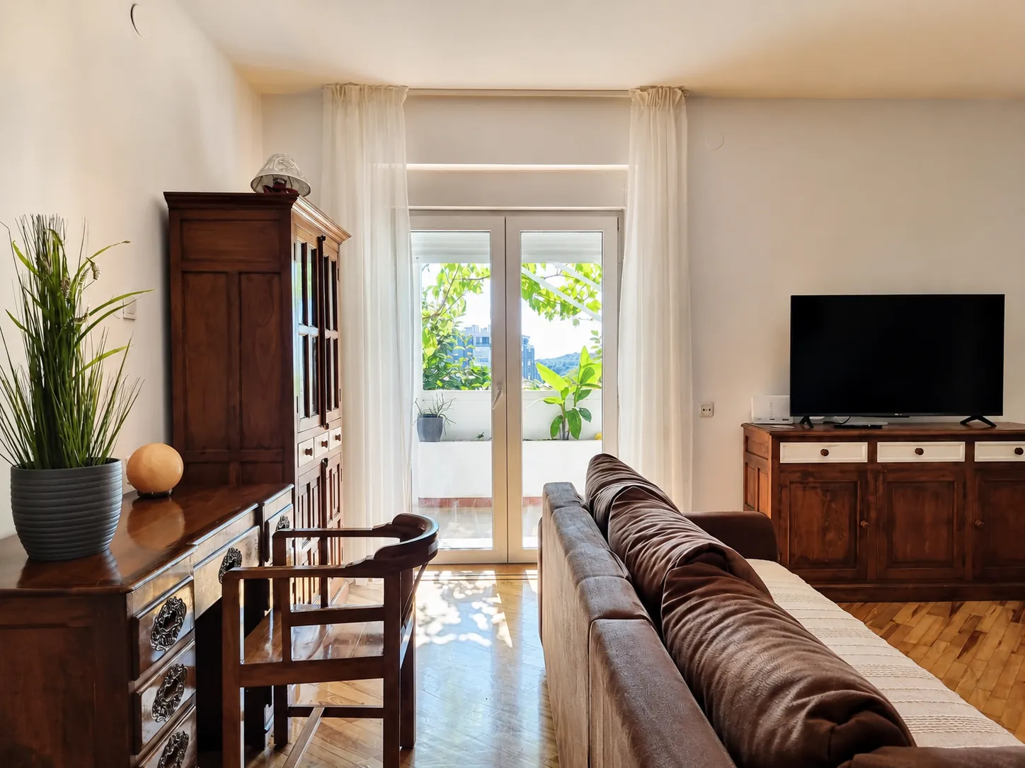 Sunlit open-plan living room of F13 Apartment with doors onto a green terrace